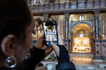 A female tourist taking photos with phone inside the Basilica di San Marco (Saint Mark's Basilica)...