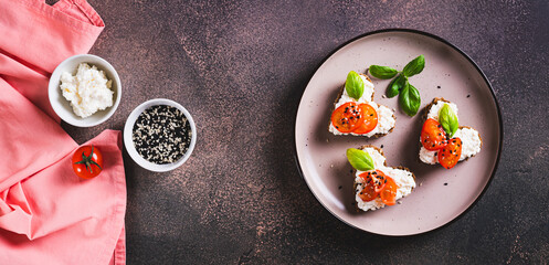 Heart sandwiches with ricotta and tomatoes on rye bread on a plate top view web banner