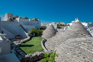 Beautiful stone of Trulli houses with white walls, narrow streets, decorated with flowers, palm...