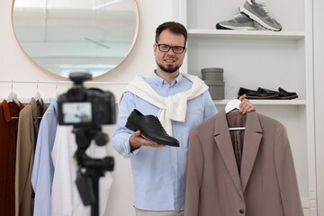 Smiling fashion blogger showing clothes while recording video at home