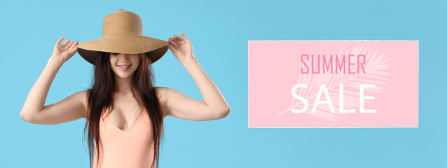 Portrait of pretty young woman in swimsuit with hat on blue background