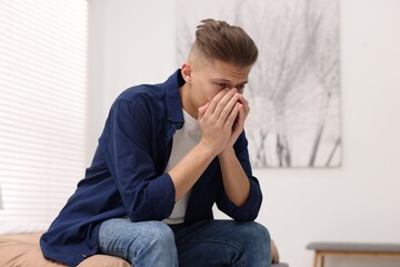 Overwhelmed man sitting on bed at home