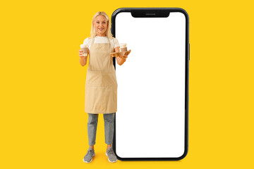 Mature woman with cups of coffee on yellow background