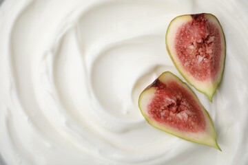 Tasty yogurt with cut fig as background, top view. Space for text