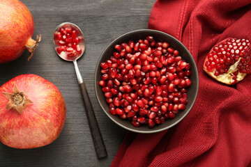 Tasty ripe pomegranates and grains on dark wooden table, flat lay