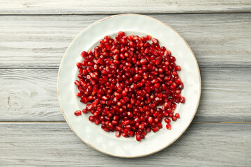Tasty ripe pomegranate grains on light wooden table, top view