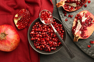 Tasty ripe pomegranates and grains on dark wooden table, flat lay
