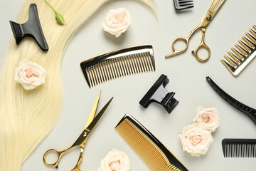 Flat lay composition with professional hairdresser tools, flowers and blonde hair strand on light...