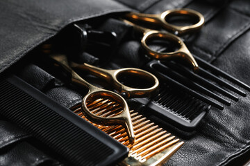 Hairdresser tools. Professional scissors and combs in leather organizer, closeup