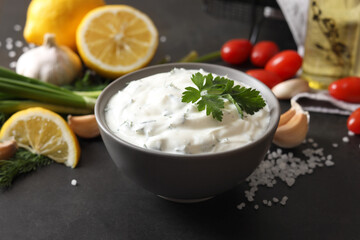 Delicious yogurt in bowl and ingredients on black table, closeup