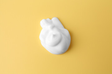 Sample of body care cream on yellow background, top view
