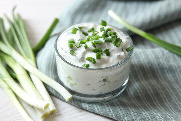 Delicious yogurt and green onion on white wooden table, closeup