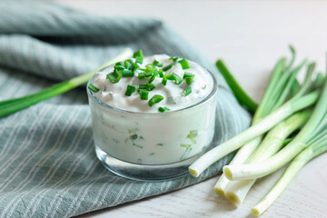 Delicious yogurt and green onion on white wooden table, closeup