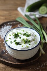 Delicious yogurt, green onion and salt on wooden table, closeup