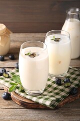 Tasty yogurt in glasses and blueberries on wooden table, closeup