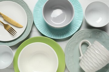 Beautiful ceramic dishware, cup and cutlery on white table, flat lay