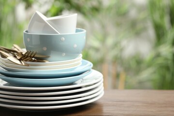 Beautiful ceramic dishware and cutlery on wooden table outdoors, space for text