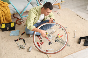 Young man repairing bicycle wheel at home