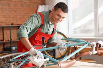 Male mechanic wiping bicycle during repair in workshop