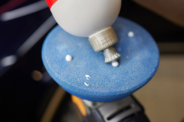 An electric blue bottle of glue rests on an automotive tire disc