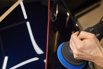 Person using machine to polish black cars automotive exterior