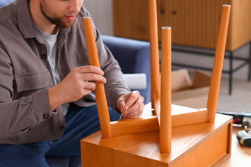 Young man assembling table at home, closeup