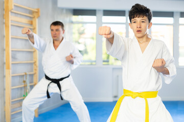 Active teenage male attendee of karate classes practicing kata in sports hall