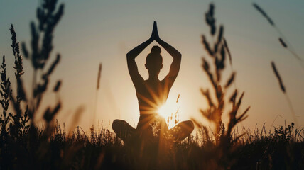 The silhouette of a woman in a yoga pose in a field at sunrise. The unity of man with nature, meditation. International Yoga Day