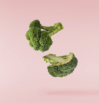 Fresh raw Brocolli cabbage falling in the air isolated on pinkk backround. Healthy food levitation. High resolution image