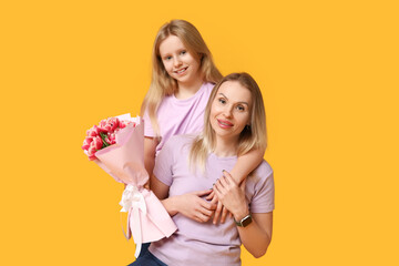 Cute little girl with her mom and bouquet for Mother's Day on yellow background