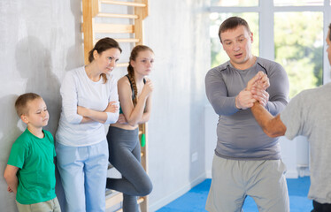 During martial art class, man coach performs painful technique and twists opponents arms,...