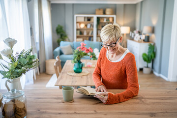 Senior woman mature caucasian female read book at home wear eyeglasses