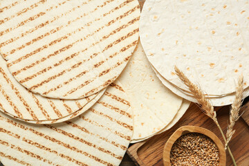 Composition with thin lavash and bowl of wheat grains on wooden background