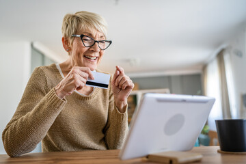 Senior woman caucasian female hold credit card online shopping at home
