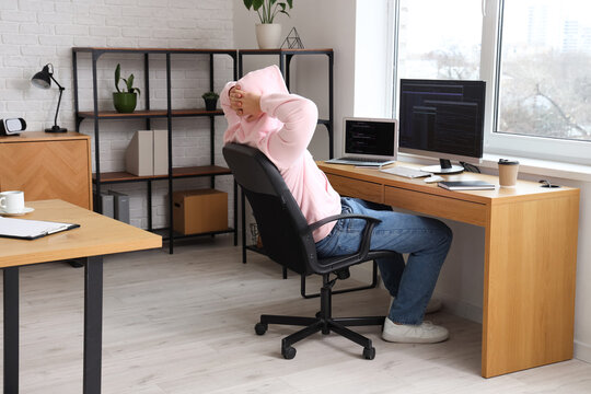 Male programmer relaxing on chair at his workspace in modern office
