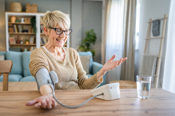 Senior caucasian woman check blood pressure measure device on hand