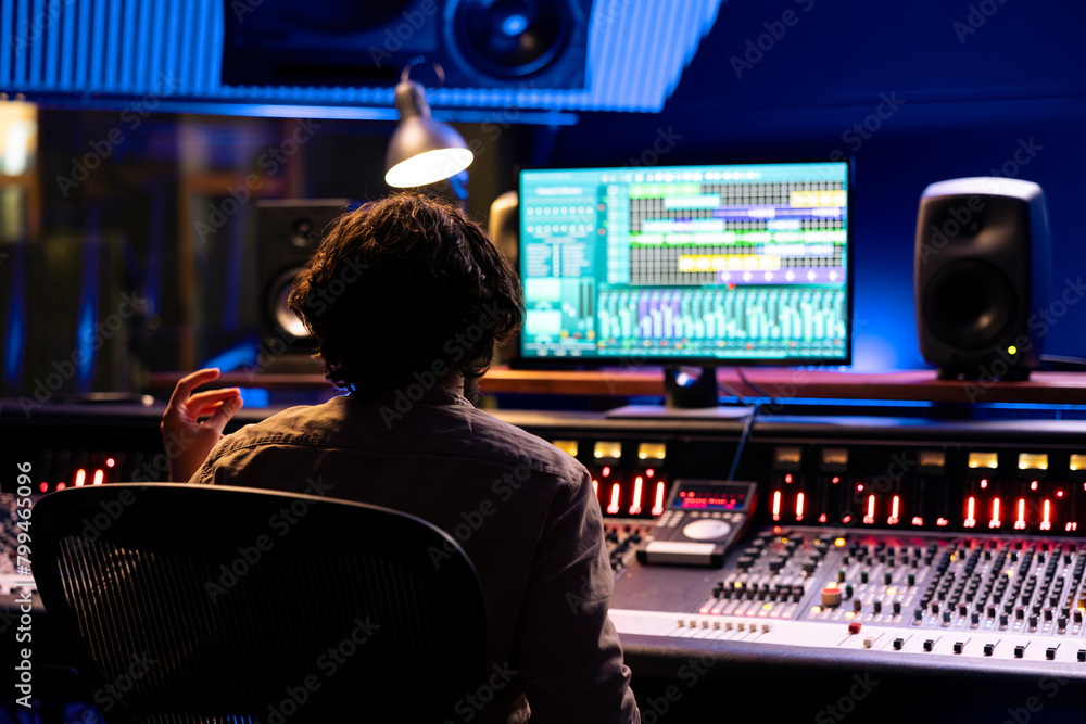 Poster Audio expert working on editing music with daw software interface, processing and mixing sounds in control room. Skilled engineer operating on control panel board console, mixer station.
