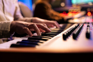 Singer songwriter creating new tracks on midi controller in studio, working with sound designer to...