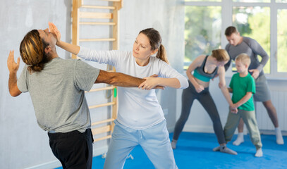 Purposeful engrossed woman train during krav maga training session and work out basic elements with...