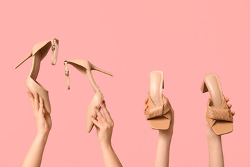 Female hands with beige sandals and stylish high heels on pink background