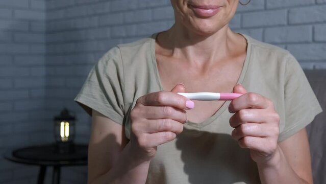 Smiling face against pregnancy test. A woman hold a pregnancy test with smile look.