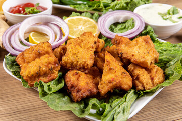 A plate of traditional Indian or Pakistani Fish Pakora, basa fish dipped in chick pea batter and deep fried