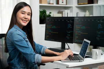 Young Asian in IT developer looking at camera to present with online information on pc with coding...