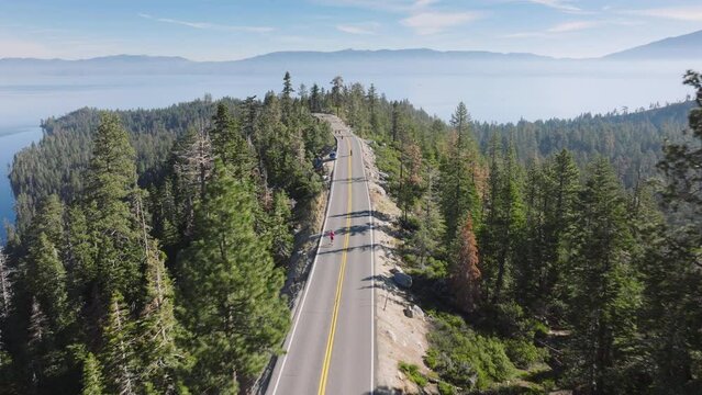 Explore a road lined with trees from above, showcasing the scenic route of Lake Tahoe, California, USA, where runners partake in competitions. 4K footage.
