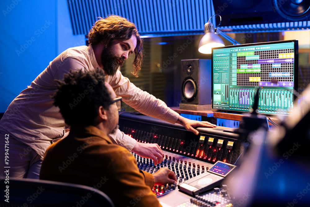 Fototapete skilled artist working with audio technician to edit recorded songs in control room, pressing slider