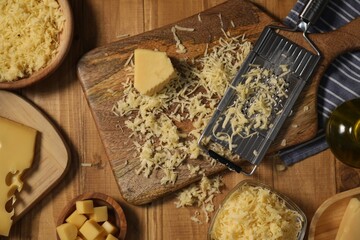Different types of cheese and grater on wooden table, flat lay