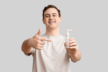 Young man with sanitizer on light background