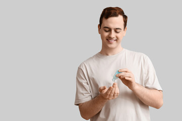 Young man with sanitizer on light background