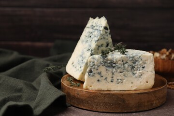 Tasty blue cheese with thyme on brown table