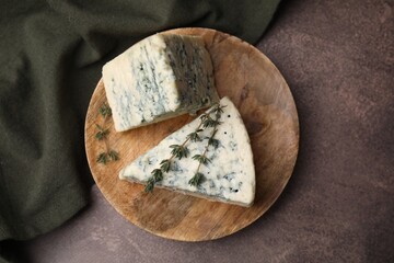 Naklejka premium Tasty blue cheese with thyme on brown table, top view